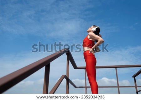female athlete in sportswear wearing wireless headphones and listening to music while out exercising. Outdoor fitness concept.