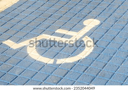 A photo of a painted white  symbol  on a blue street for handicapped people