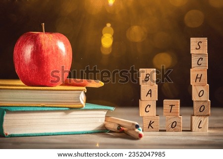 Books, apple and stationery lie on the table against the background of a black chalkboard. Education, September 1, new academic year with copy space