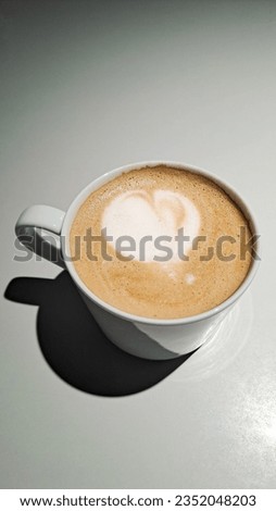 Latte art with a heart shape served with a white cup with a vignetting background