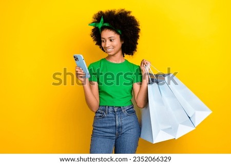 Photo of funky charming teenager schoolgirl hold store bags use smart phone online order isolated on yellow color background