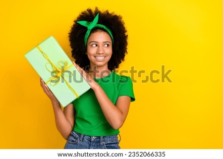 Photo of funny cheerful cute teen girl hands hold giftbox look empty space dream brainstorm isolated on yellow color background