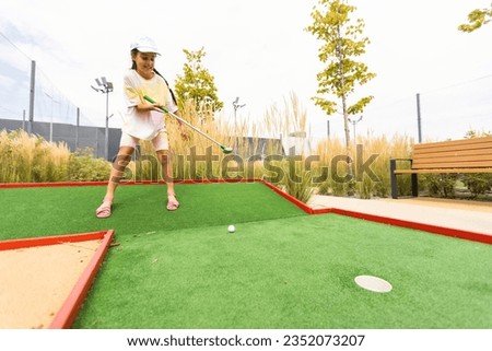 Beautiful little girl playing mini Golf Royalty-Free Stock Photo #2352073207