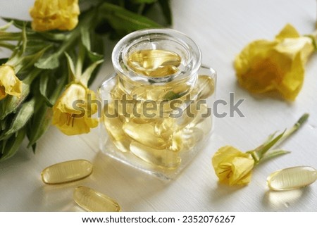 Evening primrose oil gel capsules with Oenothera biennis flowers on a white table Royalty-Free Stock Photo #2352076267