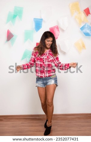 Woman dressed in character with checkered blouse dancing Forro. Sao de Joao party. Isolated on white background with colored flags.