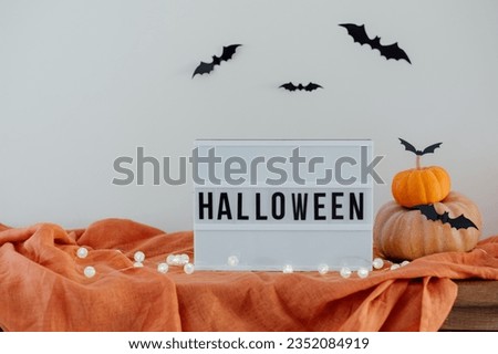 Halloween home decor. Autumn traditional holiday vibe. Sign Halloween on lightbox. 