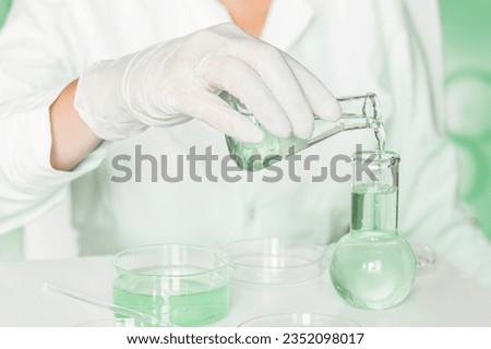 Scientific scene: Lab assistant conducts manipulations in the laboratory. Wearing lab coat. Palette of green. Glass equipment employed. Researching plants in the green laboratory.