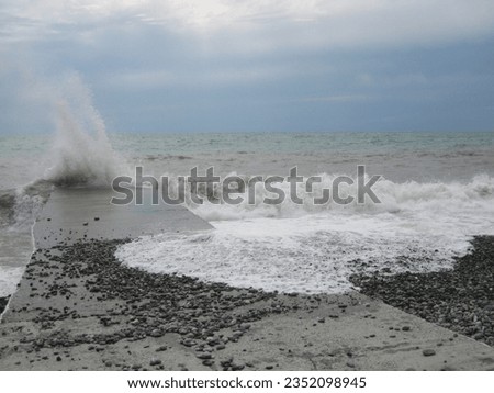 macro photo with a decorative natural background of a seascape with a sea wave and splashes on the shore and stones on the breakwater for design as a source for prints, posters, wallpaper, advertising