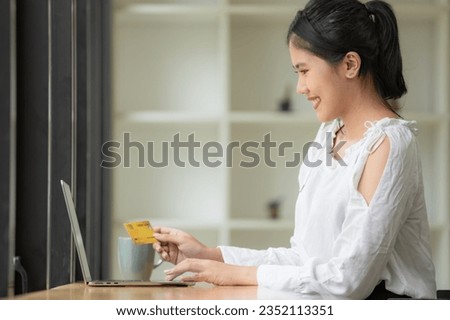 A Woman Is Holding A Credit Card, Typing on A Laptop Keyboard. There's a Notepad and a Pen next to it. The Concept of Buying Online, Ordering Products at Home, and Paying via the Internet.
