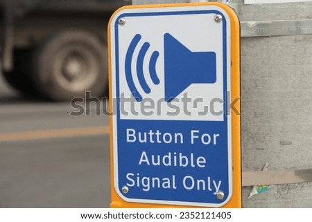 button for audible signal only crosswalk button with illustration of speaker making noise with road behind with big truck stopped, speaker pointing at tire, blue while yellow and black