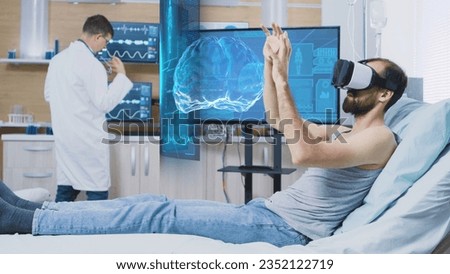 Patient laying in clinic bed wearing virtual reality headset while scientist monitors his brainwaves on screen, using medical device to enhance understanding of human mind and contribute to research