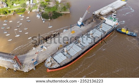 Self unloading bulk carrier arriving in South American port. Assisted by tug boat. Aerial view. Royalty-Free Stock Photo #2352136223