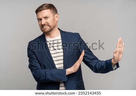 Frustrated man with disgust on serious face incredulously pushes away troubles with gesture of hands isolated on gray background. Male with angry expression refuse something bad showing denial. Royalty-Free Stock Photo #2352143435