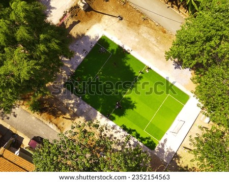 Aerial Green Football field in the middle of the Settlement. Aerial Drone Shot. Captivating Aerial View of Nature, Forest, and Lawn in a Park. Bandung - Indonesia