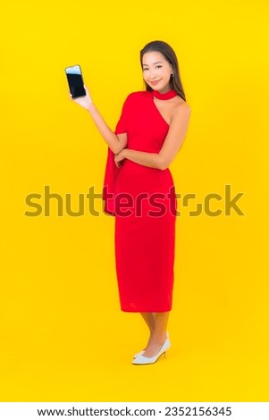 Portrait beautiful young asian woman with smart mobile phone with credit card on yellow background