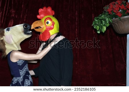 Photo Booth. Unidentifiable People wear Horse and Chicken Head Masks and pose and play while their pictures are taken in a Photo Booth. Party Photo Booth. Wedding Photo Booth. Horsing Around. Funny. 
