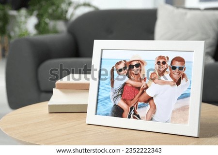 Frame with family photo and books on coffee table indoors