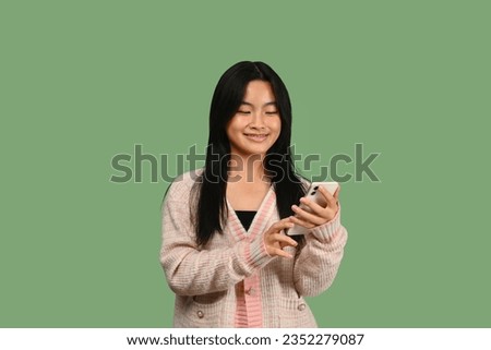 Smiling teenage girl typing text massage, chatting with friends in social media via smartphone