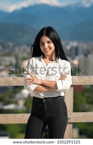 Portrait of a young happy smiling woman with folded hands in front of her in business clothes at a construction site on a sunny day. Vertical photo
