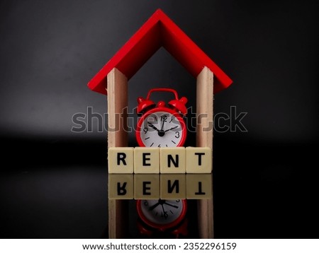 Wooden house and clock with word RENT on black background with reflection on a black acrylic board