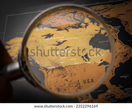 Top view hand holding magnifying glass and focus to CANADA map