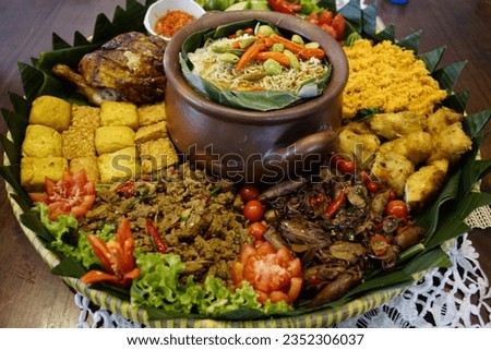 Nasi Liwet is a unique dish, for a traditional feast, savory rice, orange chili, red chili sauce, side dishes of tempeh, tofu, shrimp gimbal, cucumber, tomato, grilled chicken, lettuce leaves.