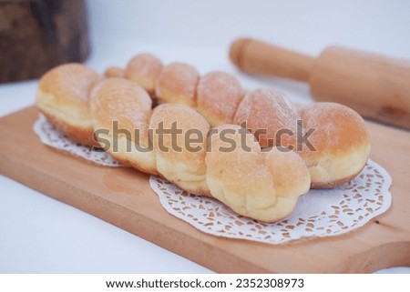 Doughnuts on wooden cutting board with rolling pin on white background
