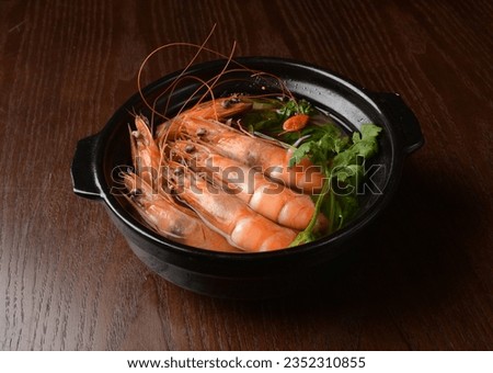 double boiled big tiger prawn poached with hot herbal soup and vegetables in black clay pot on wood table asian seafood halal food cuisine restaurant banquet menu for cafe