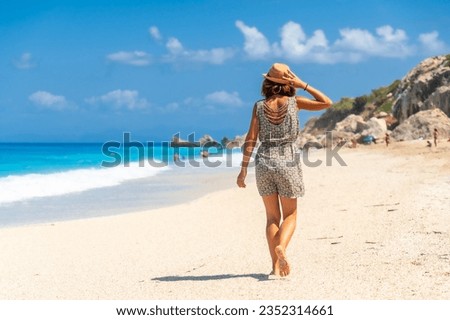 Woman with hat on Megali Petra beach with turquoise water of Lefkada island, Ionian Sea, Greece