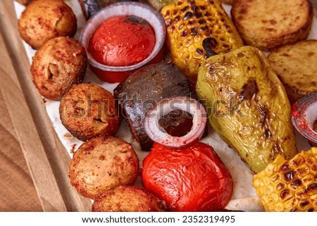 Fried vegetables on the wooden board - zucchini, eggplant, bell peppers, mushrooms, corn, red onion with spices, close-up, shallow depth of field