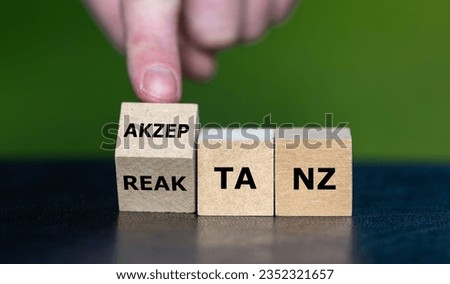 Hand turns wooden cube and changes the German word 'akzeptanz' (acceptance) to 'reaktanz' (reactance).