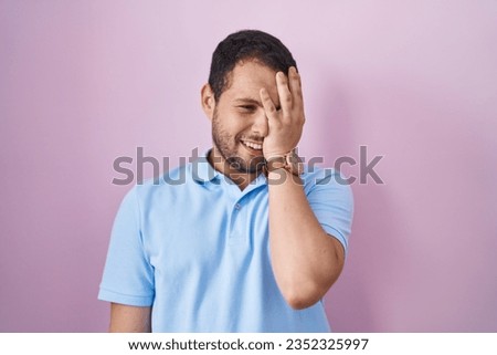 Hispanic man standing over pink background yawning tired covering half face, eye and mouth with hand. face hurts in pain. 