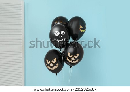 Different black Halloween balloons and folding screen near blue wall in room