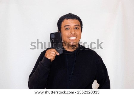 Adult Asian man wearing black sweater holding his mobile phone with very happy expression.