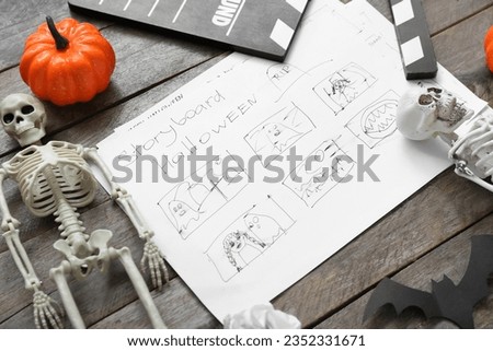 Clapperboard with storyboard and Halloween decor on brown wooden background