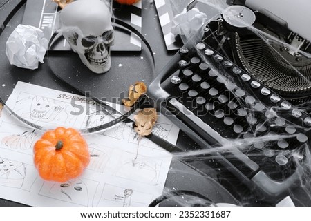 Typewriter with storyboard, film reel and Halloween decor on grunge grey background