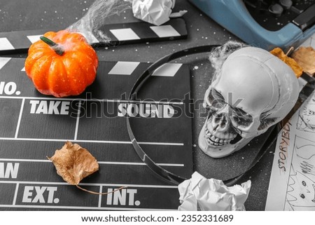 Typewriter with clapperboard, film reel and Halloween decor on grunge grey background