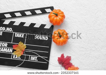 Clapperboard with Halloween decor on textured white background