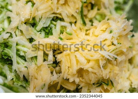 Shredded raw zucchini and potatoes fill the picture. Background of zucchini mucver