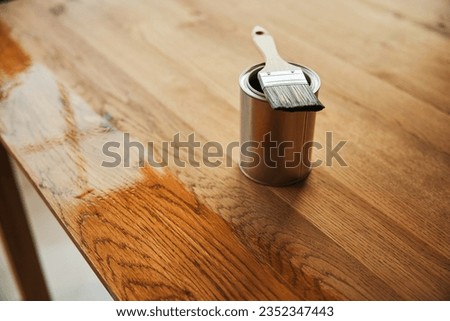 Picture of brush and oil can on the wooden table during oiling renovation process.