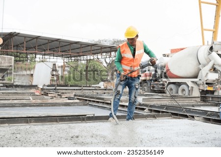 Asian male builder worker uses concrete vibration generator during levelling concrete. Male mason working and using concrete vibrator removal air bubbles for maximum strength in concrete Royalty-Free Stock Photo #2352356149
