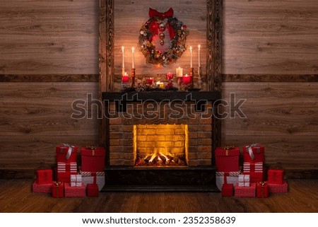 Many gift boxes near the Christmas fireplace in a festive interior of a Log Cabins with wooden walls. Mantelpiece with candles, Christmas wreath with bells and bow
