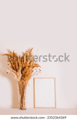Wooden poster photo frame mock up with dry flowers plant vase. Copy space.