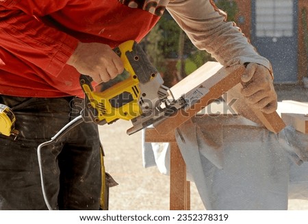 Closeup of a carpenter cutting with a jig saw the beech wood stair step of a staircase for the interior of a house. Carpentry work for the integral reform of a two story house Royalty-Free Stock Photo #2352378319