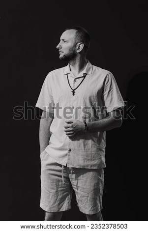 A stylish man with a cross around his neck, black and white picture.