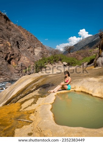 Young Peruvian Woman Wearing a Bikini and Shorts Poses in the Santo Tomas Hot Springs near the River in Abancay, Peru 
