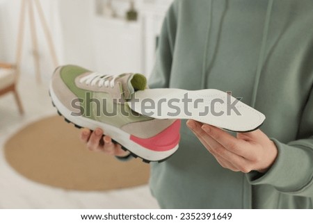Woman putting orthopedic insole into shoe at home, closeup. Foot care Royalty-Free Stock Photo #2352391649