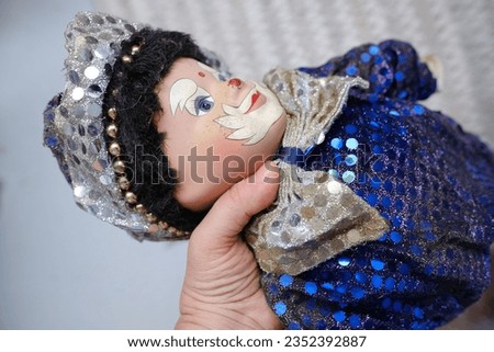 female hand with clown in blue shiny suit, abandonment, loss and resilience, Collectibles and Antiques, Therapeutic Value of Collecting