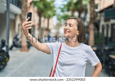 Middle age woman smiling confident making selfie by the smartphone at street