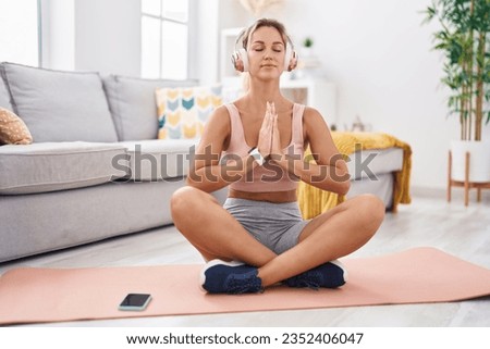 Young blonde woman doing yoga exercise sitting on floor at home